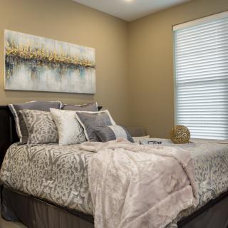 Cozy bedroom with stylish bedding and artwork on the wall.