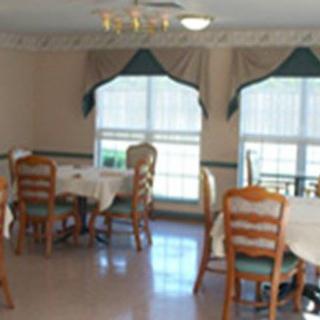 A dining room with several tables and chairs arranged near large windows.