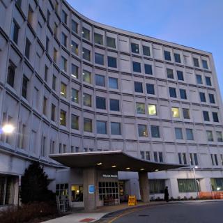 A modern hospital building illuminated at dusk.