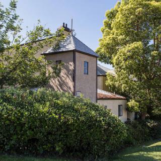 A quaint house nestled among lush greenery, surrounded by trees and a vibrant garden.