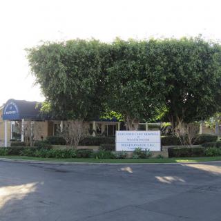 A building entrance with a sign and dense trees in the background.