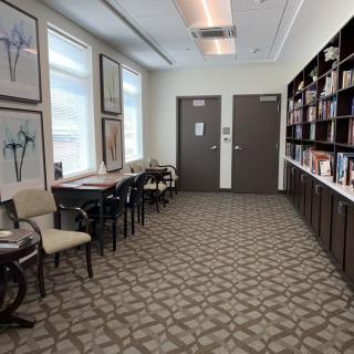 A quiet waiting room with chairs, a bookshelf, and artwork on the walls.