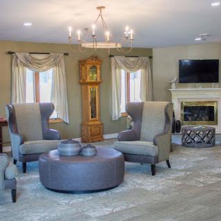 A beautifully designed living room featuring cozy armchairs, a modern chandelier, and an elegant fireplace.