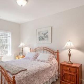 A cozy bedroom with a wooden bed, matching nightstands, and two lamps.