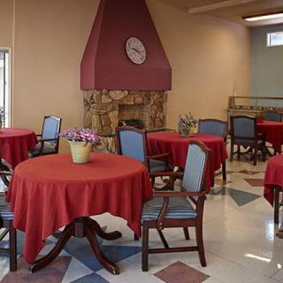 A cozy dining room with red tablecloths and a fireplace.