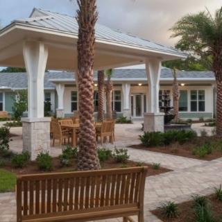 A serene outdoor patio area with benches and palm trees in front of a modern building.