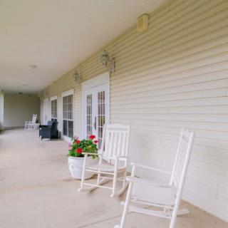 A peaceful porch with white rocking chairs and potted plants.