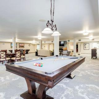 A spacious game room featuring a pool table and comfortable seating areas.