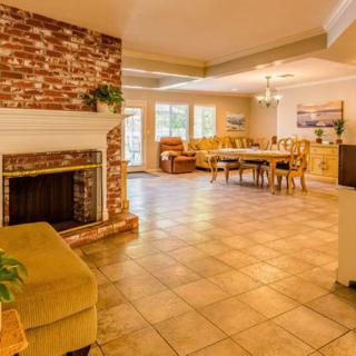 A spacious living and dining area with a brick fireplace and tiled flooring, showcasing an open floor plan.