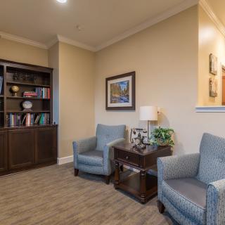 A cozy living room with two armchairs, a wooden bookshelf, and decorative items.