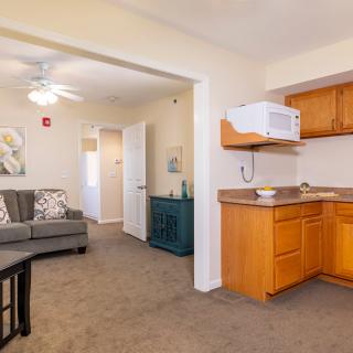 A cozy apartment interior featuring a living room with a sofa and a small kitchen area.