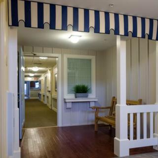 A cozy hallway interior featuring a wooden bench, striped awning, and decorative plant.