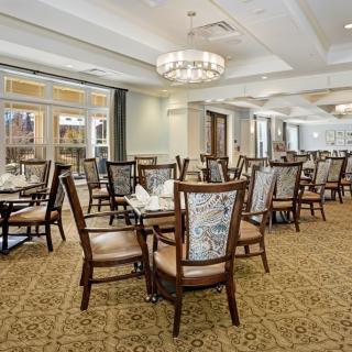 An elegant dining room with neatly arranged tables and chairs under a chandelier.