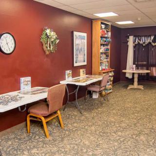 A cozy room with red walls, featuring tables and chairs, a clock, and decorative artwork.