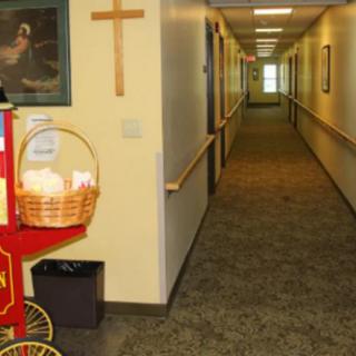 A hallway featuring a popcorn cart, religious cross, and artwork on the wall.