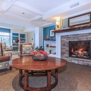 A cozy living room featuring a wooden table, comfortable chairs, and a warm fireplace.