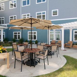 Outdoor patio area with tables, chairs, and umbrellas in front of a building.