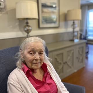 An elderly woman sitting in a chair in a cozy living room setting.