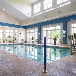 An inviting indoor swimming pool with large windows allowing natural light to brighten the area.