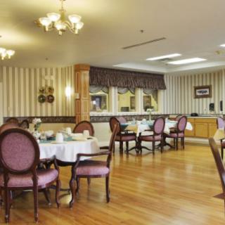 A spacious and elegantly decorated dining room with neatly arranged tables and chairs, featuring wooden flooring and stylish lighting fixtures.