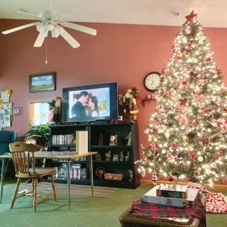 A cozy living room decorated for Christmas with a beautifully lit tree and presents.