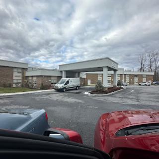 A view of a commercial building from a parking lot under a cloudy sky.