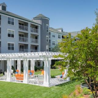 A residential apartment building with a pergola on a well-maintained lawn.