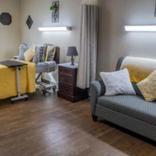 A cozy hospital room with a bed, sofa, and bedside table.
