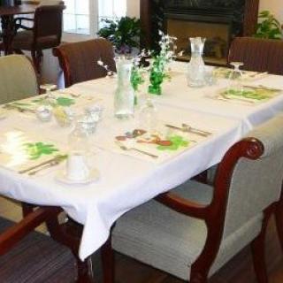 A dining table set for a meal, featuring a white tablecloth, glassware, and decorative centerpieces.