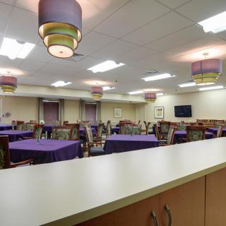 A modern dining area featuring tables with purple tablecloths and stylish lighting.