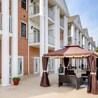 A multi-story building with grand columns and an outdoor patio area featuring a gazebo and seating.