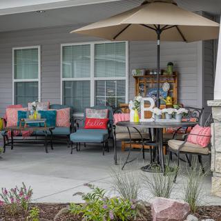 A cozy patio setup featuring colorful seating, a dining table with an umbrella, and decorative elements.