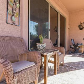 A cozy patio area with wicker chairs, a small table, and decorative elements basking in sunlight.