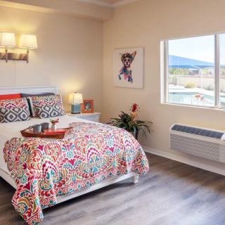 A cozy bedroom with colorful bedding and natural light streaming in through a large window.