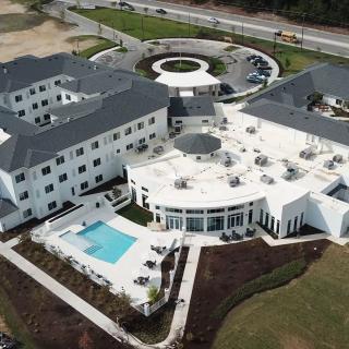 Aerial view of a modern hotel with a pool and landscaped surroundings.