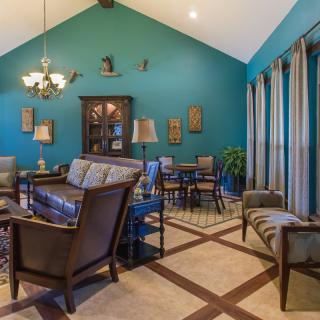 A cozy living room with teal walls, featuring elegant furniture and a dining area under a vaulted ceiling.