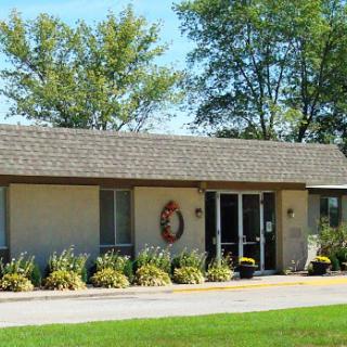 A charming single-story building surrounded by well-maintained landscaping and trees.
