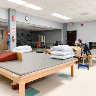 A spacious physical therapy room equipped with exercise tables and various rehabilitation tools.