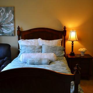 A cozy bedroom with a neatly made bed, warm lighting, and elegant decor.