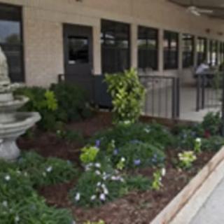 A landscaped garden with a fountain outside a building.