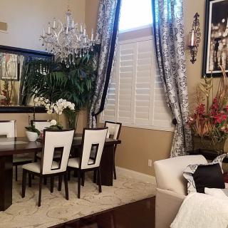 An elegant dining room with a chandelier, mirror, and stylish curtains.