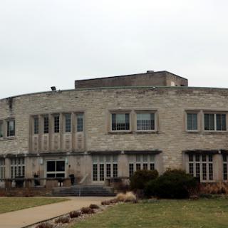 A unique stone building with multiple windows, surrounded by a landscaped area.