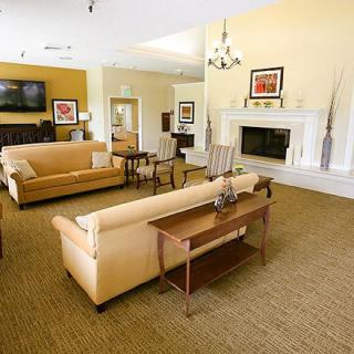 A cozy living room featuring beige couches, a fireplace, and a television.