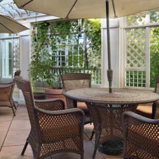 A tranquil outdoor patio with wicker furniture and umbrellas, surrounded by lush greenery.