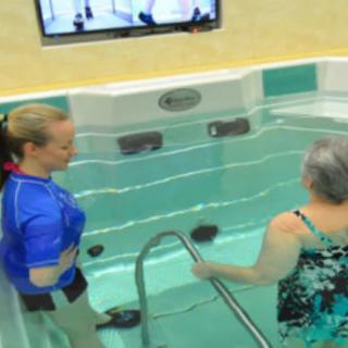 A therapist guides a senior woman in an aquatic therapy session for rehabilitation.