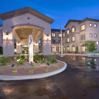 A beautifully designed modern building entrance at night, featuring elegant lighting and landscaped surroundings.