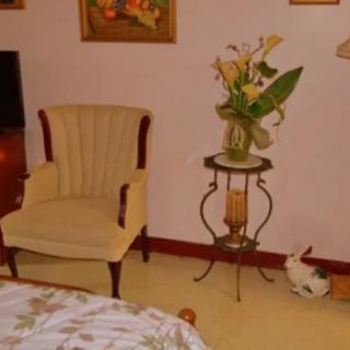 A cozy living room setting with an armchair, a side table holding a vase of flowers, and framed artwork on the walls.