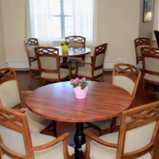 A cozy dining room with round tables and comfortable chairs.
