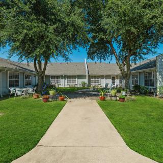 A well-maintained residential courtyard with a central sidewalk, surrounded by trees and landscaping.
