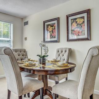 An elegant dining room with a round table and upholstered chairs, adorned with wall art and tasteful decor.